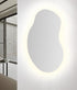 Espejo Nebula sin marco, diseño orgánico moderno con silueta fluida, botón táctil y retroiluminación LED perimetral para baño o vestidor.